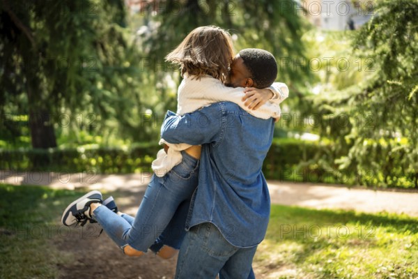 Multi-ethnic couple in love embracing and jumping together in a park