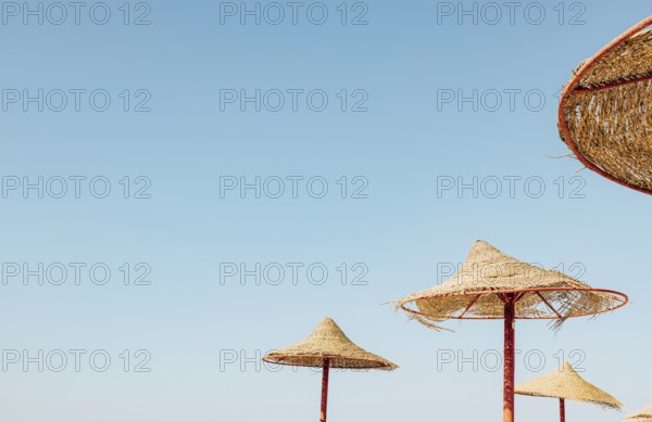 Looking up at wooden straw umbrella or thatched hut from below against beautiful cloudy blue sky