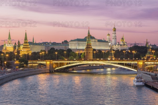 Illuminated Moscow Kremlin and Moscow River with bridge in the summer evening. Pink sky. Russia