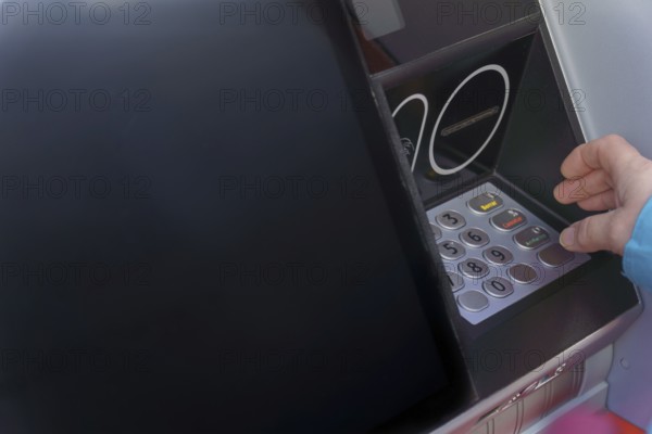 Woman typing her PIN number into an ATM machine to withdraw cash