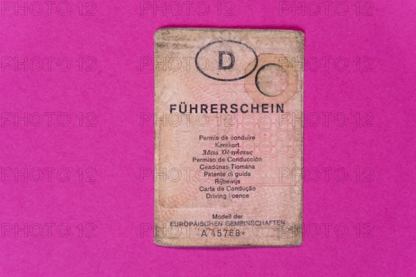 Pink old driving licence against a pink background