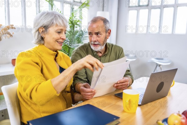 Senior couple looking at financial bills using laptop together at home