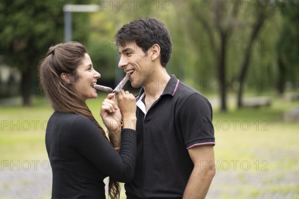 Young couple in love eating a popsicle in the park