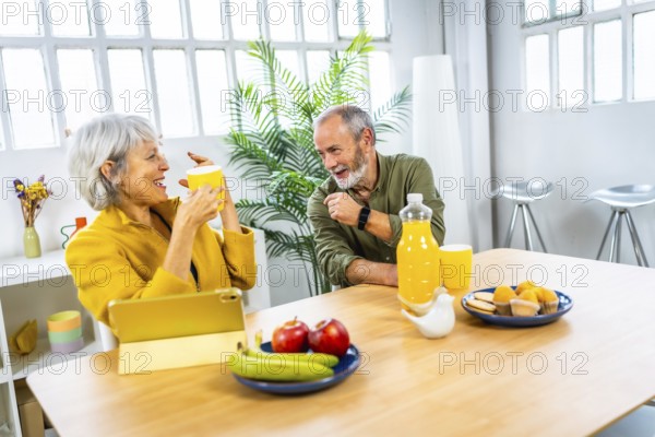 Happy senior couple enjoying a healthy breakfast in the living room at home