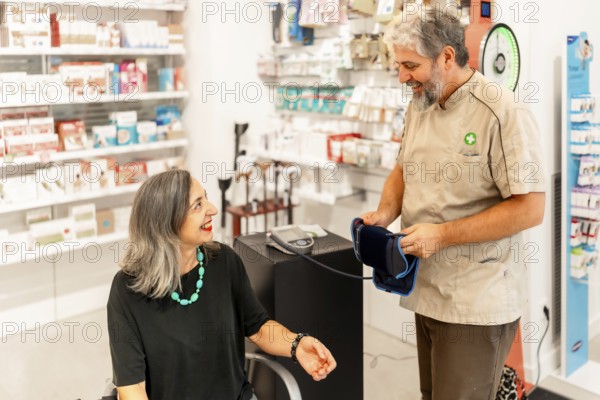 Pharmacist preparing machine to measure blood pressure to a woman sitting in the pharmacy store