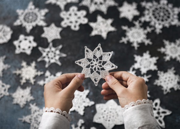 A crocheted snowflake, star made of white cotton in the girl's hands as a small handmade Christmas