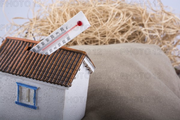 Thermometer measuring high temperature placed on a little model house