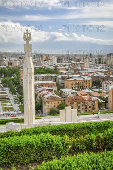 Photo of large monument surrounded by greenery and buildings of capital city Yerevan in Armenia