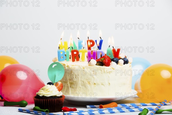 Tasty cake with berries happy birthday title near balloons