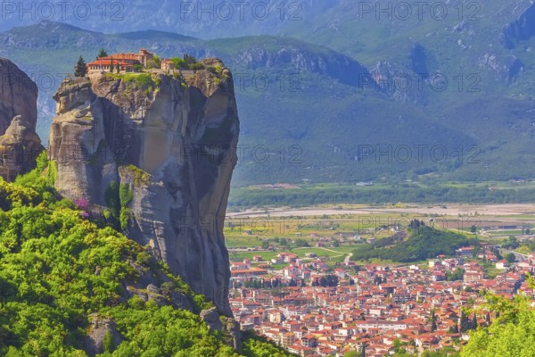 Holy Trinity Monastery on cliff rock top, Meteora, Greece and Kalampaka town in the valley
