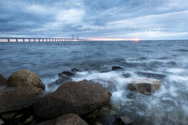 The view of the rough sea with a dramatic sky and a bridge in the background, Öresund Bridge,