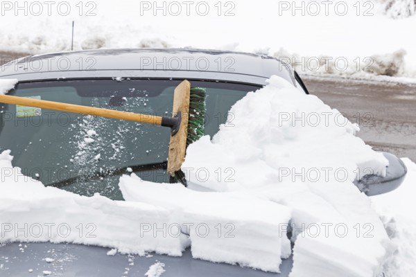 Sweeping a snow-covered car with a broom
