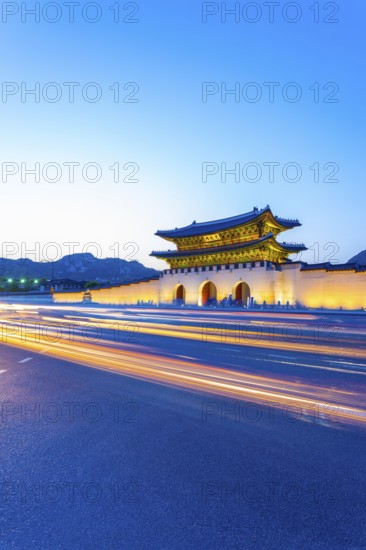 Colorful streaking car lights passing in front of lighted gate of Gwanghuamun, entrance to historic