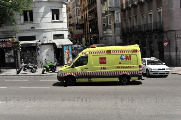 Madrid, Spain, Europe, Yellow ambulance on the street in a city, surrounded by buildings and other