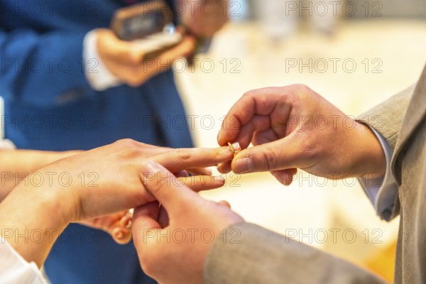 A man and woman are getting married and the man is putting a ring on the woman's finger