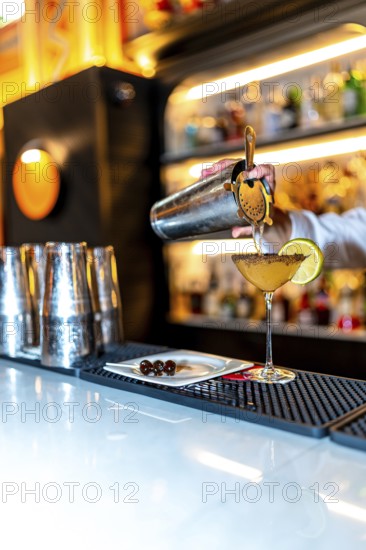 Vertical photo of an unrecognizable bartender preparing a luxury cocktail on a bar