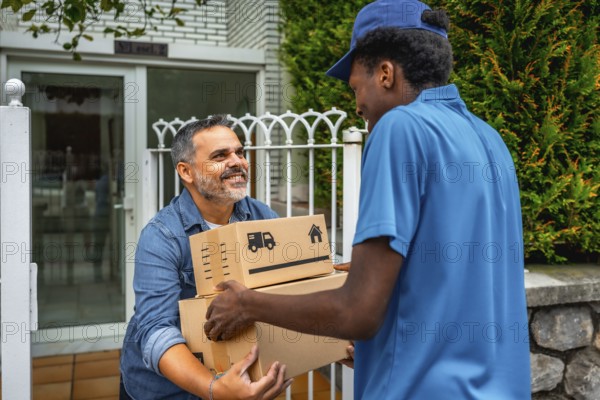 African delivery man giving packages to a costumer at home standing next to the entrance