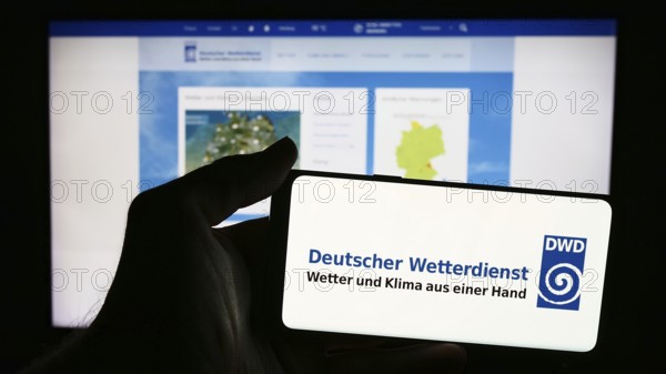 Stuttgart, Germany, 06-06-2024: Person holding mobile phone with logo of German meteorological