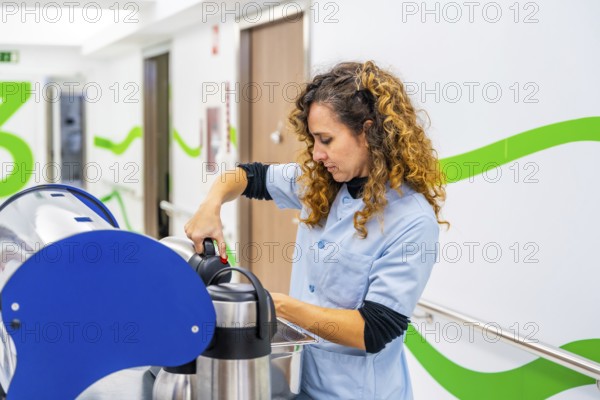 Nurse pouring coffee into cup in the corridor of an hospital using a trolley to carry it