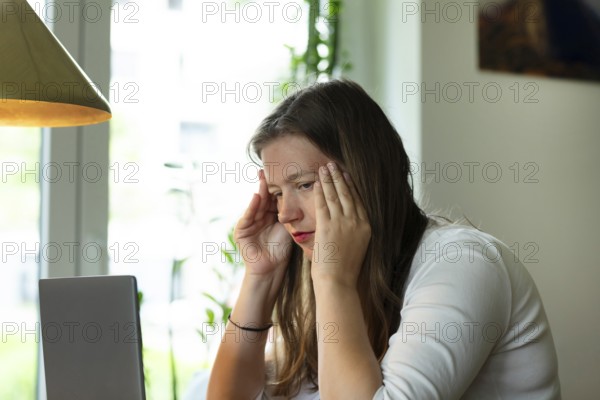 Young woman suffers from burnout in home office on laptop, Freiburg, Baden-Württemberg, Germany,