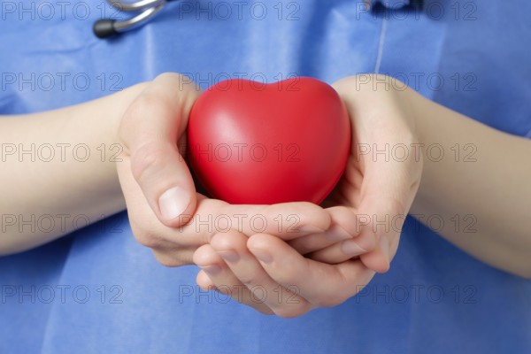 Female doctor holding a red heart shape