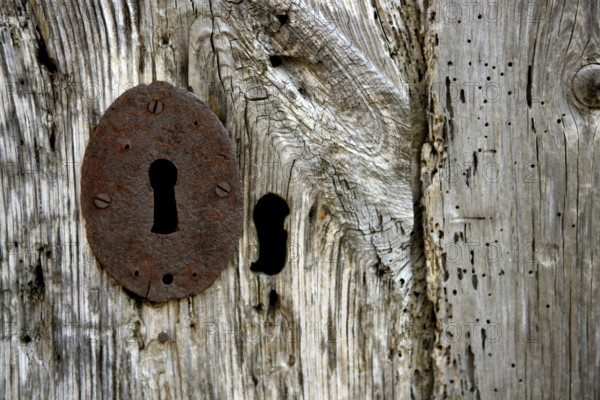 Key hole over aged gray old wood, rusty metal