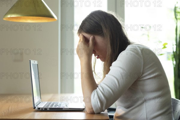Young woman suffers from burnout in home office on laptop, Freiburg, Baden-Württemberg, Germany,