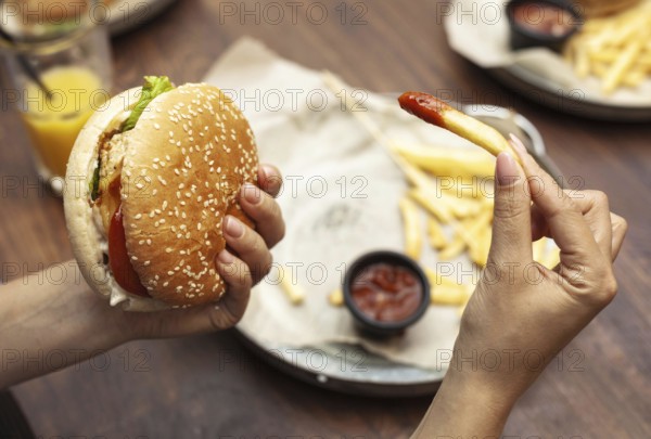 High angle person eating burger french fries
