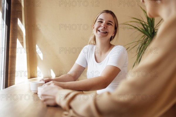 Happy young female friends having coffee break while relaxing at indoor cafe