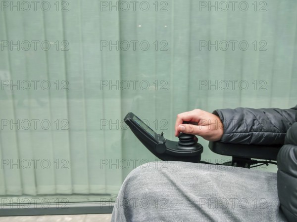 Close up of a disabled person hand driving electric wheelchair using joystick