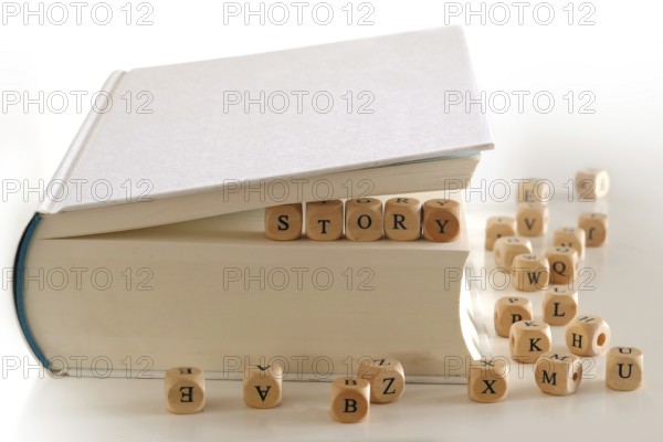 Story, message for creativ writing spelled with wooden letter blocks between pages of a white book,