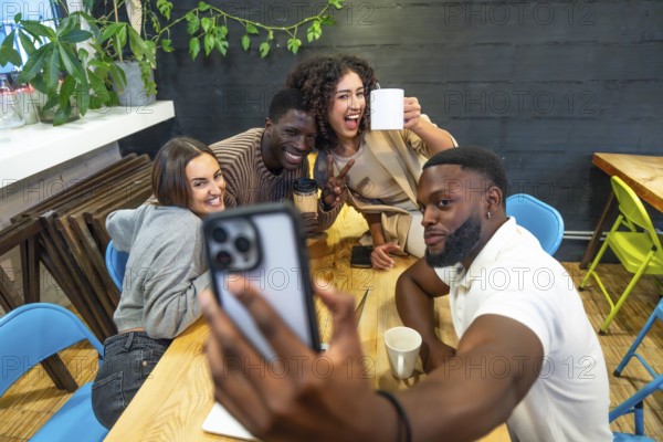 Diverse coworkers smiling taking selfie in the cafeteria of a modern coworking space