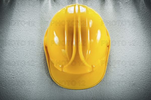 Yellow safety cap on concrete background View from above