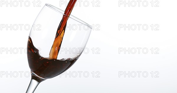 Red Wine being poured into Glass, against White Background