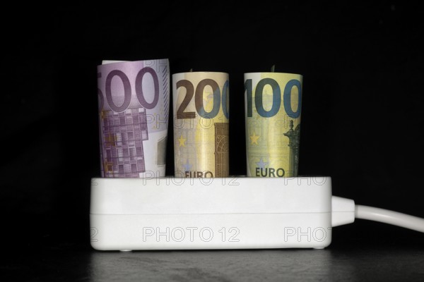 Symbol photo for electricity costs, socket with 3 banknotes, 500 €, 200€ and a 100€ banknote,