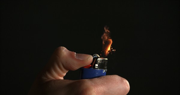 Lighter in Hand with Flame against Black background