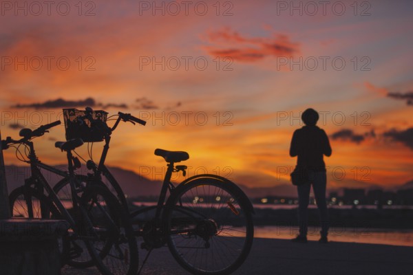 Person standing bicycle sunset
