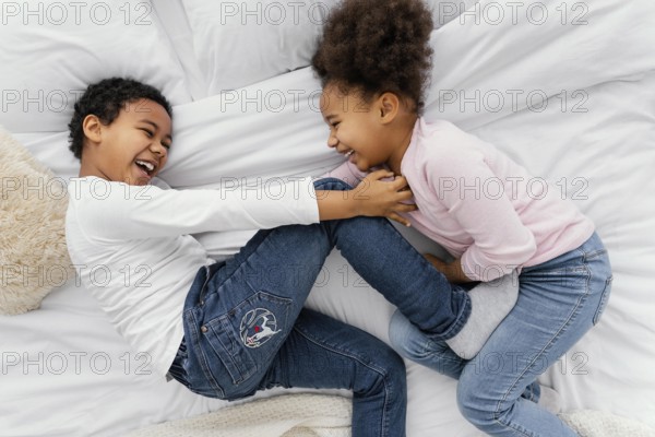Top view two siblings playing bed home together