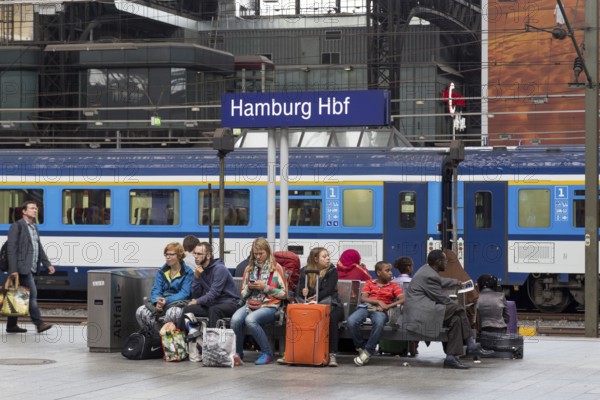 Hamburg, Germany, August 5, 2016: Group of people sitting under a signpost on the platform of the
