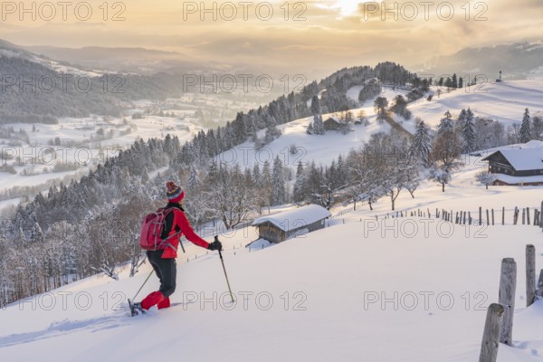 Pretty active senior woman snowshoeing in the Allgäu Alps near Oberstaufen with a view of the