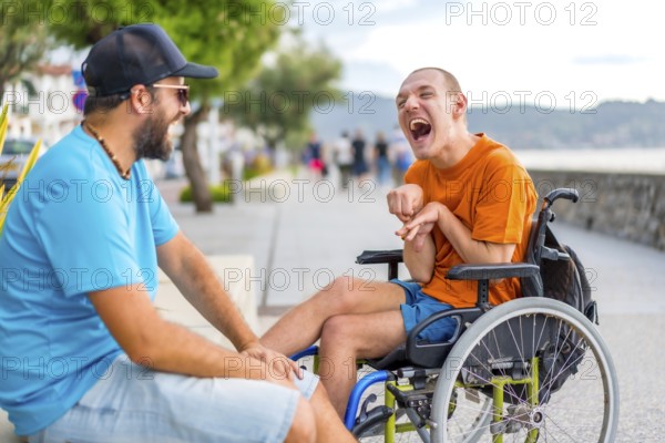 A disabled person in a wheelchair with a friend on summer vacation having fun laughing a lot