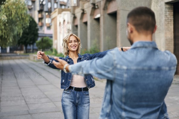 Happy meeting of two lovers hugging in the street. Young woman greeting her boyfriend embracing