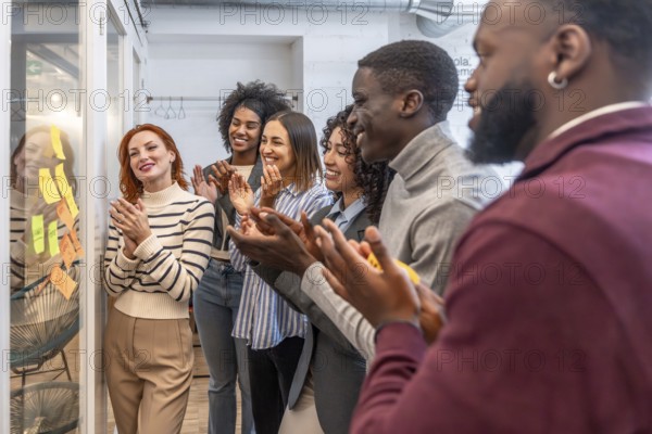 Diverse females and males mulit-ethnic colleagues applauding after a successful meeting in a modern