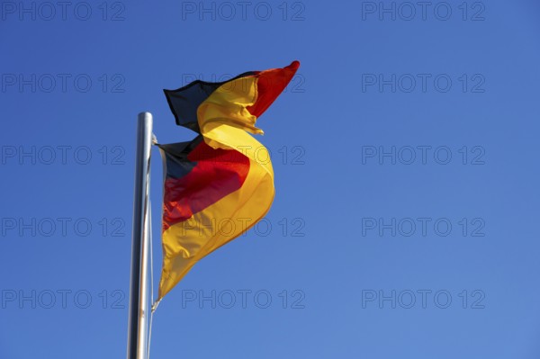 German flag, national flag in strong wind against blue sky