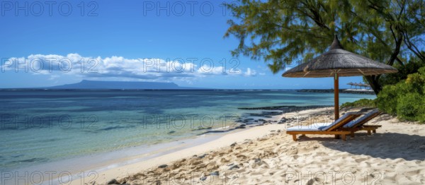 Tropical beach scene with lounge chairs under an umbrella, clear blue sky, and calm ocean waters,
