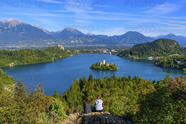 Two people at Osojnica Hill watching the view of Bled Island and Lake Bled, a popular tourist