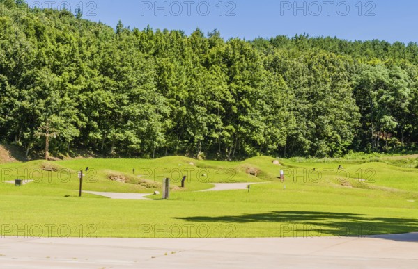 Royal tombs with entrances of stone next to treeline at Neungsa Baekje Temple, South Korea, South