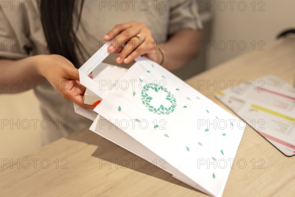 Pharmacist introducing a package of medicine into a paper bag for a client in the counter of the