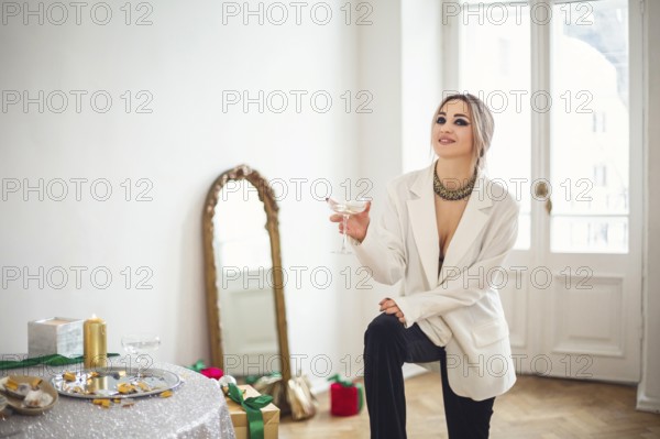 Young woman wearing sparkly sequin holiday dress sitting with alcohol drink in front of