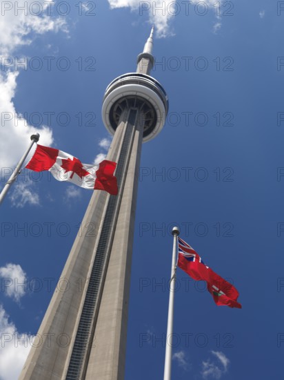 Ontario and Canada flags flying in front of Toronto CN tower over blue sky